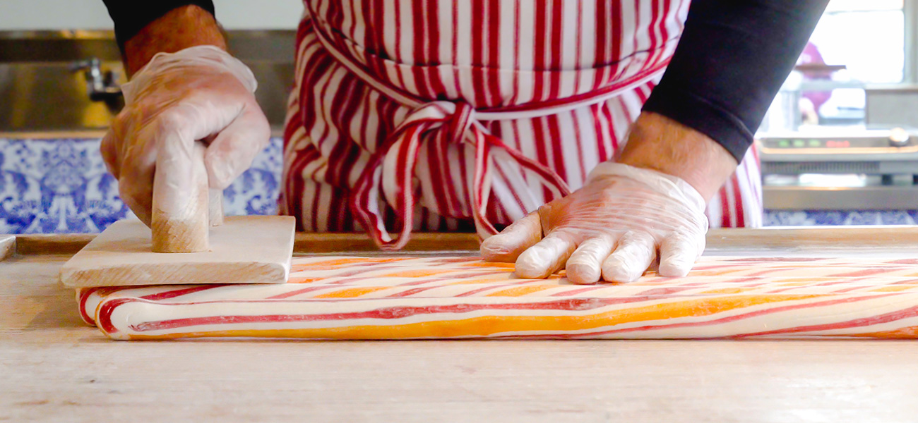 Person creating peppermint candy at a candy factory.