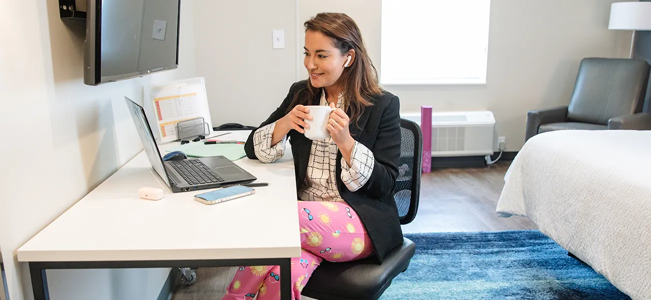 Woman at a computer working remote from an Extended Stay America hotel room